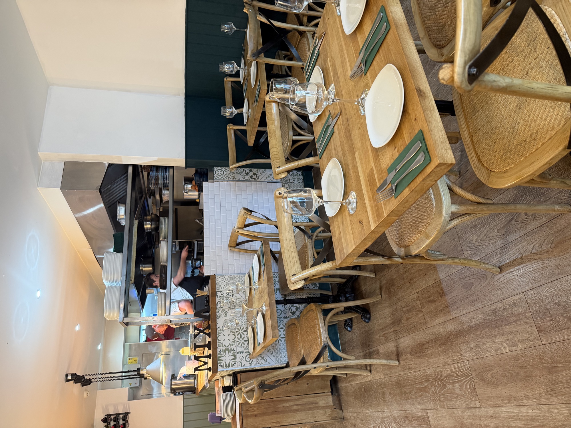 MIXA dining room with open kitchen, wooden MIXA letters and oregano-green panelling