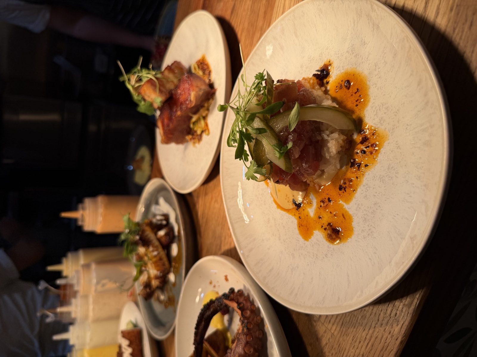 Chefs plating octopus, tartare and pork belly at the kitchen pass