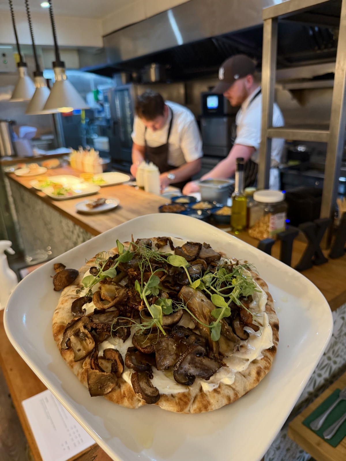 Chef holding mushroom flatbread from the open kitchen
